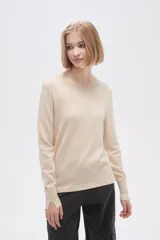 Sweater color beige de tejido de punto, con cuello redondo y mangas largas con abertura en el puño.
