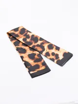 Pañuelo rectangular con estampado abstracto en tonos terracota, negro, blanco y beige.