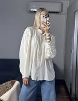Camisa blanca de mangas largas con detalles de encaje en el cuello y en el frente.