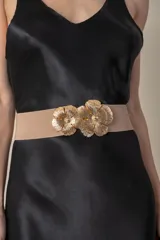 Cinto elástico color beige con hebilla metálica dorada con forma de dos flores.