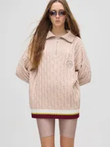 Sweater tejido de algodón color rosa claro, con cuello polo con cierre de cremallera metálica y mangas largas con puños a rayas de colores.