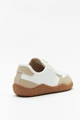 Zapatillas de cuero color blanco y beige, de diseño minimalista con suela marrón.