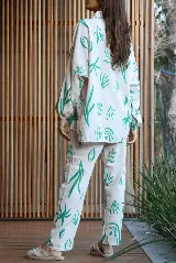 Conjunto de camisa de manga larga y pantalón largo, ambos con estampado de motivos vegetales en color verde sobre fondo blanco. La camisa es de corte oversized y el pantalón tiene bolsillos laterales.
