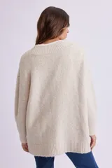 Cardigan de punto color crema, con escote en V, cierre frontal con botones marrones y corte holgado.