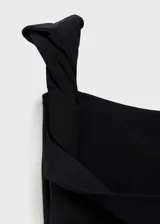 Vestido largo de fiesta negro, con diseño asimétrico, un tirante ancho y escote off-shoulder. Presenta detalles fruncidos y cierre lateral con cremallera.