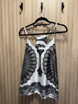 Top blanco con estampado abstracto en tonos negro, marrón y celeste. Tiene breteles finos y espalda racerback.