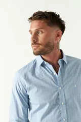 Camisa celeste a cuadros, de corte slim fit, manga larga y logo bordado. Confeccionada en 100% algodón.