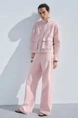 Pantalón de jean color rosa, de tiro alto, corte recto y largo hasta el tobillo. Presenta bolsillos de parche delanteros y traseros, trabillas en la cintura y cierre frontal con cremallera y botón.