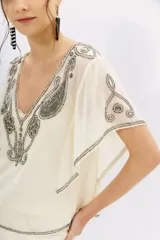 Blusa color crema de georgette con bordado de piedras, mostacillas y canutillos. Viso interior con puntilla.