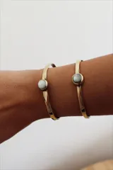 Pulsera rígida de bronce con piedra redonda de nácar engarzada.