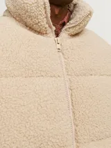 Campera puffer color beige de tela tipo teddy, con cuello alto, cierre frontal con cremallera, bolsillos laterales y puños elásticos.