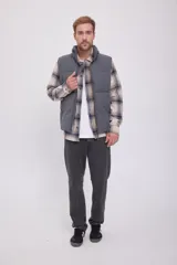 Chaleco puffer gris sin mangas con cuello alto y cierre de cremallera.