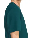 Remera de hombre Adidas Essentials, color verde oscuro, con tejido texturizado tipo gofre o waffle. Presenta cuello redondo con costura en forma de V invertida (mock stitch) y el logo del trébol (Trefoil) bordado en blanco en el pecho.