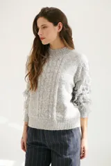 Sweater color arena de tejido de punto con cuello redondo y mangas largas con flecos.
