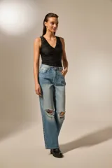 Pantalón jean negro con roturas en las rodillas, diseño de estrellas metálicas a lo largo de las costuras laterales y en los bolsillos delanteros.