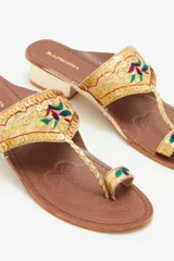 Sandalia de cuero color marrón con bordados de hilo y lentejuelas doradas. Tiene taco cuadrado color hueso de 3 cm de altura.