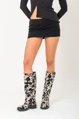 Bota de cuero con estampado animal print de vaca, caña alta y taco bajo.