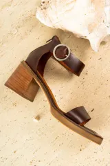 Sandalias de cuero color crudo, con tira ancha sobre los dedos, pulsera con hebilla al tobillo y taco cuadrado de madera.