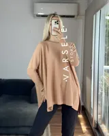 Maxisweater color crudo, de tejido símil bremer, talle único (abarca hasta 2xl). Presenta detalles en las mangas, aperturas laterales y es más largo en la parte trasera.
