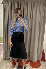 Falda midi negra de jean con corte evasé y costuras diagonales.