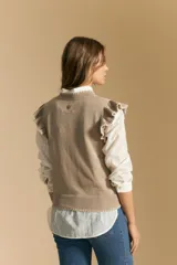 Top tejido sin mangas color negro, con cuello redondo y volados en las sisas con terminación en contraste de punto blanco. Presenta un calce recto y puño inferior acanalado con detalle de punto blanco.