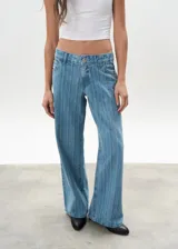 Pantalón de jean celeste con rayas verticales, tiro bajo y corte wide leg.