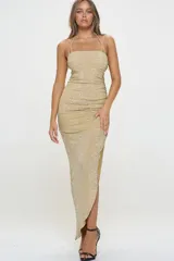 Vestido largo de fiesta dorado con breteles finos y espalda descubierta. Diseño ajustado al cuerpo con frunces laterales y abertura en la falda.