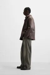 Sobrecamisa marrón de efecto piel con interior de borreguillo combinado a tono, de corte relaxed fit, cuello solapa, manga larga con puños abotonados, bolsillos de plastrón en pecho y laterales en cadera, efecto lavado y cierre frontal con botones a presión.