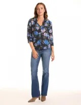 Camisa de gasa con estampado floral de rosas azules y rosadas sobre fondo negro. Presenta cuello con solapa, escote en V y abertura central con botones. Las mangas son largas y se pueden ajustar con una presilla y botón.