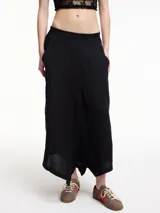 Pantalón negro de lino, tiro medio, corte amplio, con bolsillos laterales y pretina elástica en la parte trasera.