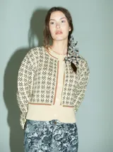 Cardigan de punto color borgoña con diseño geométrico en blanco y detalles en azul. Tiene cuello redondo, cierre frontal con botones rojos y mangas largas con puños acanalados.