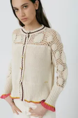 Cárdigan azul con detalles en crochet, mangas con volado y vivos de color rojo en cuello, puños y frente. Tiene botones al frente.