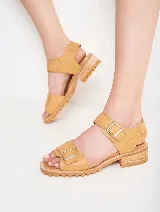Sandalias de cuero color ocre con doble tira sobre el empeine y hebillas metálicas plateadas. Suela de goma con plataforma baja y detalle de costuras.