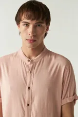 Camisa lisa color salmón con cuello mao y mangas cortas con dobladillo.