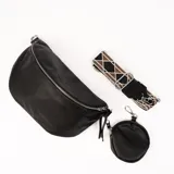 Riñonera negra de cuero con correa de tela estampada y monedero redondo con cierre.