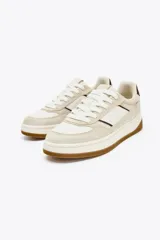 Zapatillas deportivas urbanas color beige y blanco, con detalles en color borgoña en el talón y laterales. Cierre con cordones y suela marrón de 3,5 cm de altura.