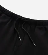 Pantalón baggy color beige, confeccionado en algodón con felpa. Presenta cintura elástica con cordón ajustable, bolsillos delanteros y un bolsillo trasero. El bajo es ajustable con elástico.