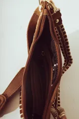 Cartera de hombro negra con forma de media luna, confeccionada en material con textura de pelo o cuero. Presenta costura decorativa gruesa en el borde y correa ajustable con herrajes metálicos plateados.