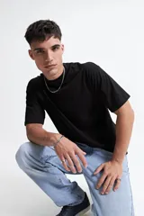 Remera negra de manga corta con corte boxy, cuello redondo y hombros caídos.