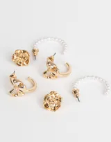 Set de tres pares de aros dorados: argollas con moño, argollas con perlas y aros pasantes con forma de flor.