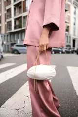 Bolso de mano rígido con forma ovalada irregular y efecto perlado. Tiene laterales metalizados, asa de cadena extraíble y cierre metálico.