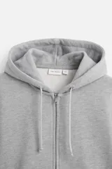 Sudadera negra relaxed fit de algodón compacto con interior en rizo, cuello con capucha ajustable, manga larga, bolsillos frontales tipo canguro, acabados en rib y cierre frontal con cremallera.