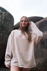 Buzo beige de corte holgado, tejido acanalado y cuello redondo. Estampado frontal con la frase "Glassy Waves Beach Life".