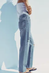 Pantalón de jean celeste de tiro alto, corte mom fit, largo regular y roturas en las rodillas.