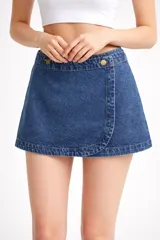 Minifalda de jean azul con diseño cruzado y botones dorados en la cintura.