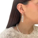 Aros colgantes de acero plateado con dije rectangular de circonias blancas.