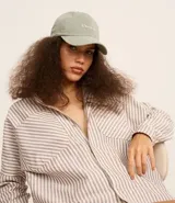 Gorra de sarga color verde claro con ala curva y bordado frontal con la frase "C'est la vie". Ajuste trasero con hebilla.