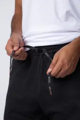 Pantalón de jogging gris claro con puños elásticos, cintura con cordón ajustable y estampado con motivos geométricos en la pierna izquierda.