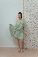 Vestido corto color beige de lino, con escote redondeado con lazo y mangas cortas amplias.