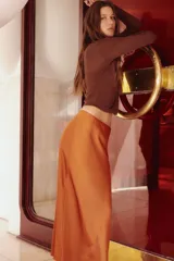 Pollera midi color naranja de tejido fluido con caída suave, elástico oculto en la cintura y bajo con leve vuelo.